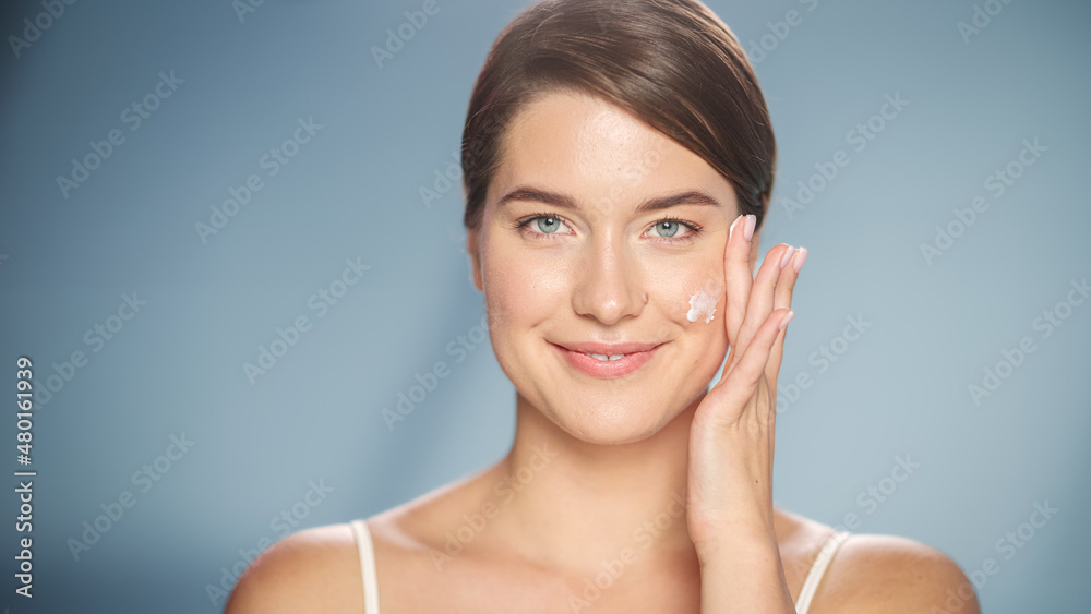 Female Beauty Portrait. Beautiful Caucasian Woman with Brown Hair Touching Natural, Healthy Skin, Using Facial Moisturizer, Applying Face Cream. Wellness and Skincare Concept on Isolated Background. Female Beauty Portrait. Beautiful Caucasian Woman with Brown Hair Touching Natural, Healthy Skin, Using Facial Moisturizer, Applying Face Cream. Wellness and Skincare Concept on Isolated Background.
