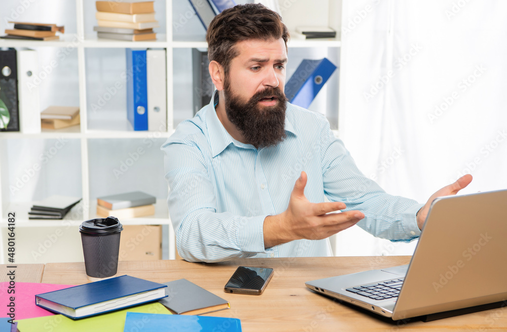 Disappointed businessman working on laptop at office desk, work
