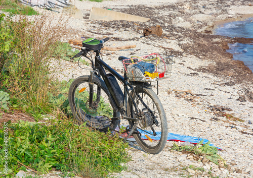 a tourist's bicycle stands on the pebbly seashore. the concept of tourism and travel