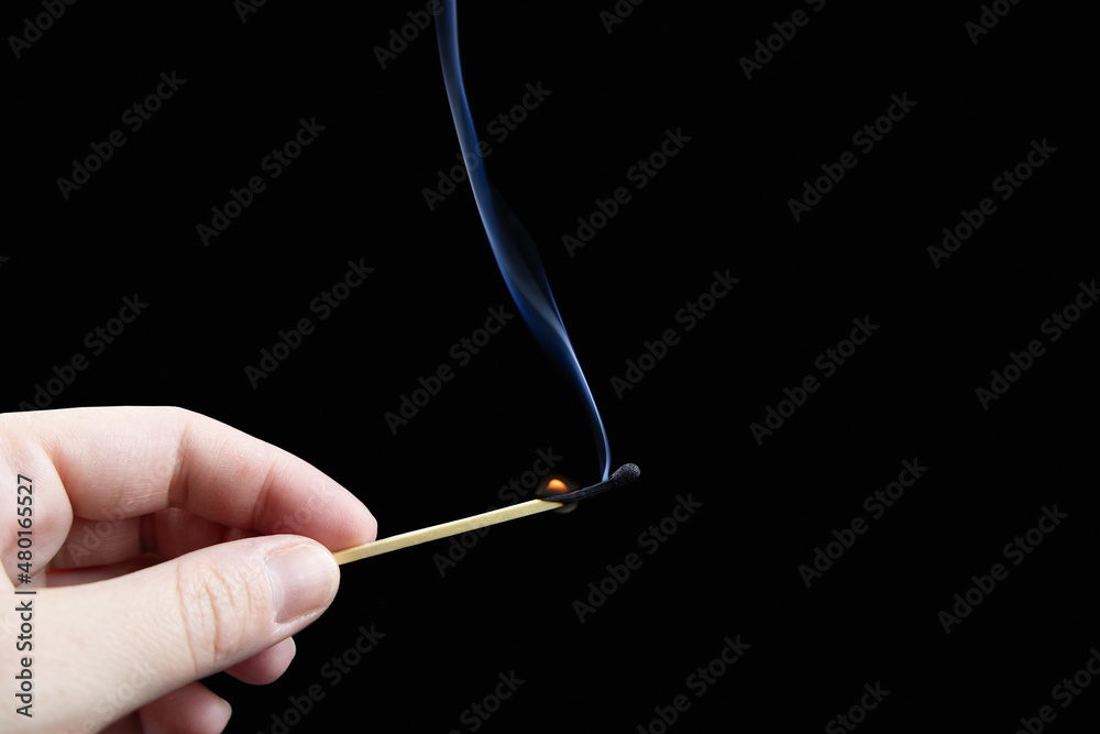 Almost extinct match with plume of smoke in fingers on black background Almost extinct match with plume of smoke in fingers on black background