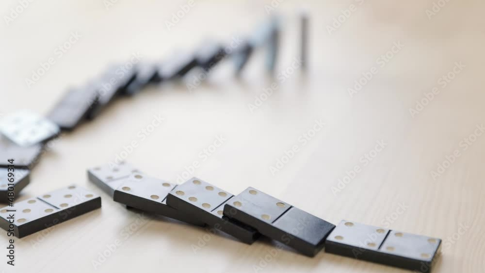 Falling dominoes. Chain reaction, built figure of dominoes falling in slow motion.