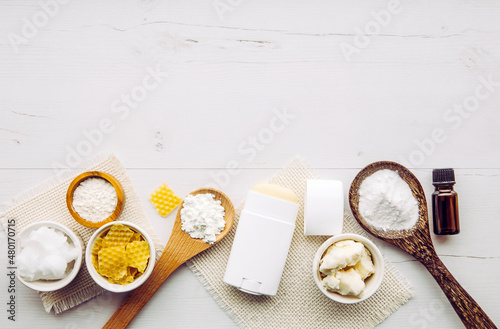 Making homemade deodorant stick with all natural ingredients concept. White wood background. Ingredients: arrowroot powder, baking soda, beeswax, shea butter, essential oil, cornstarch, coconut oil.