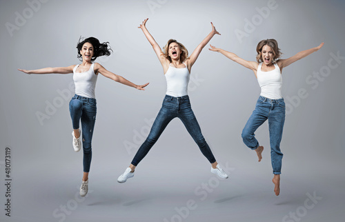 Group of beautiful young women wearing white shirt and denim jeans having fun