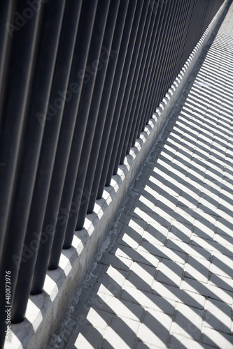 Shadows from the fence on the asphalt