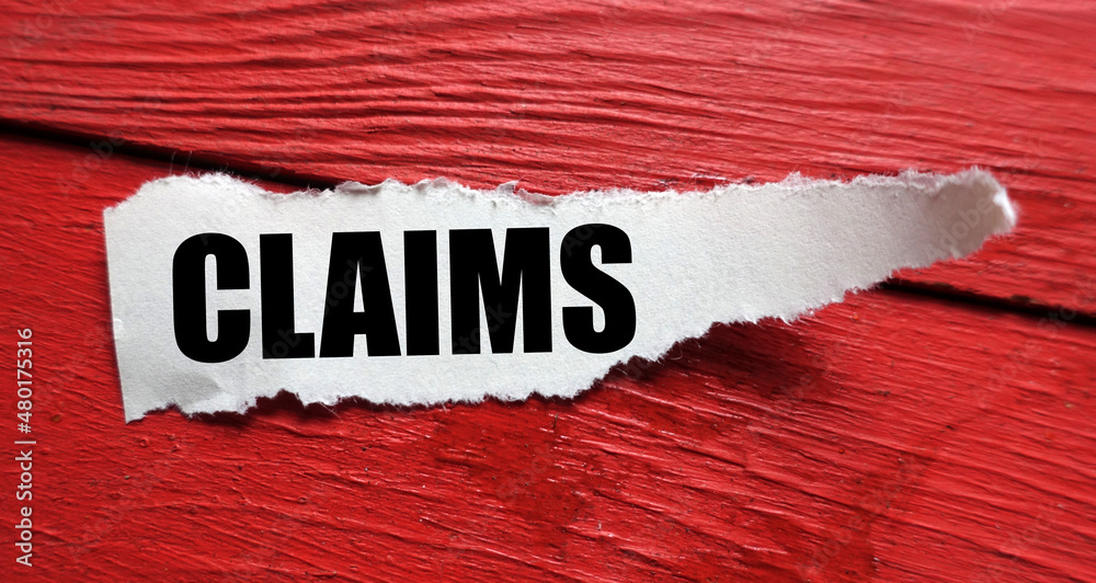Fototapeta premium CLAIMS word on a small sheet of paper and a red table.