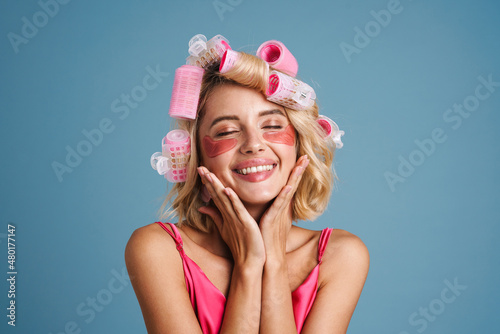 Fotografi Young woman with curlers and eye patches smiling at camera
