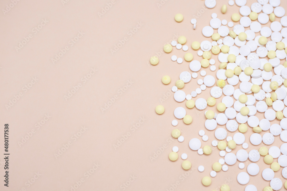 Concept of medicine, nursing and pharmacy. White and yellow pills scattered on beige table. Appearance for advertising, web backgrounds or other ideas. Copy space. Concept of medicine, nursing and pharmacy. White and yellow pills scattered on beige table. Appearance for advertising, web backgrounds or other ideas. Copy space.