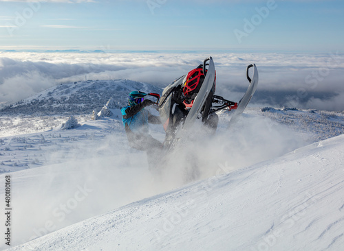 extreme driving of a mountain snowmobile. a sports snowmobiler in bright clothes and a helmet without brands, a colorful snowmobile of a new model. jumping with plumes and whirlwinds of snow