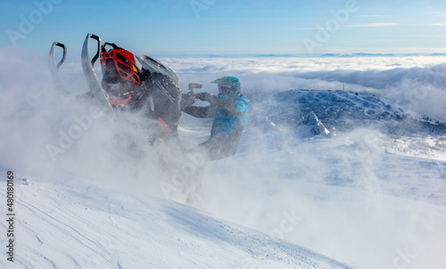 extreme driving of a mountain snowmobile. a sports snowmobiler in bright clothes and a helmet without brands, a colorful snowmobile of a new model. jumping with plumes and whirlwinds of snow