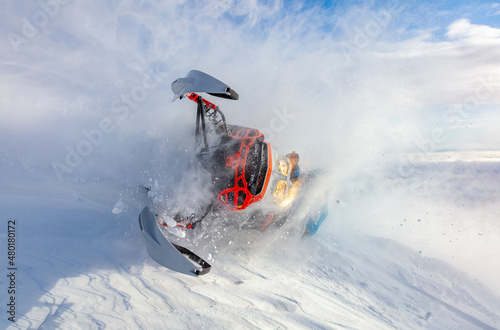 a beautiful and steep turn of a snowmobile in a close-up fall. a very rare photo of a snowmobile extreme with heavy snow in the frame. the concept of winter outdoor activities in the mountains