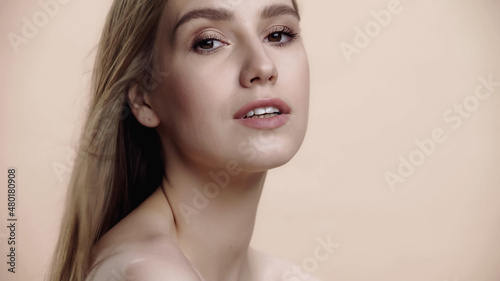 young woman with natural makeup and bare shoulders isolated on beige.