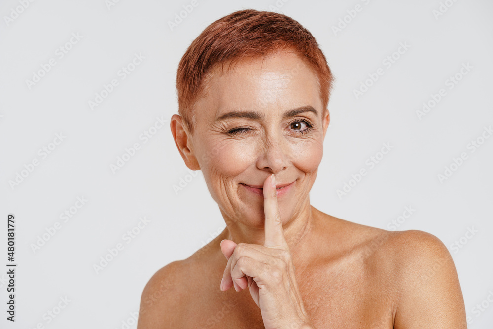 Senior shirtless woman winking and showing silence gesture Senior shirtless woman winking and showing silence gesture