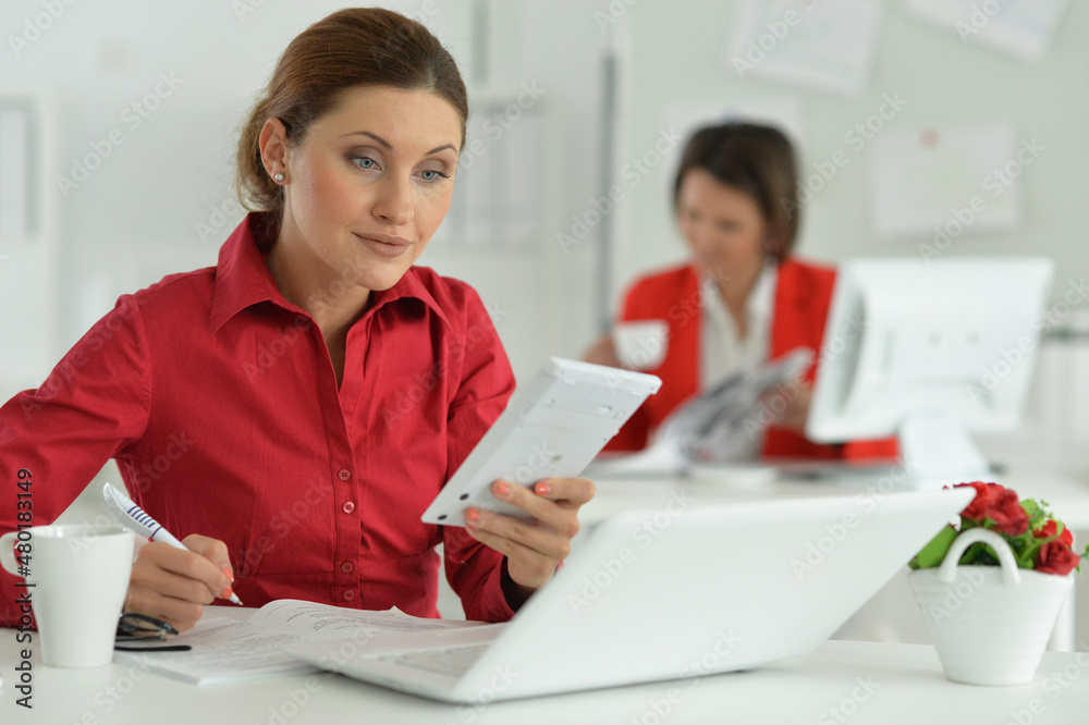 Businesswoman architect working with calculator in modern office with her colleague Businesswoman architect working with calculator in modern office with her colleague