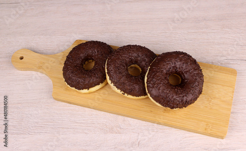 Round donuts in chocolate on a wooden cutting board