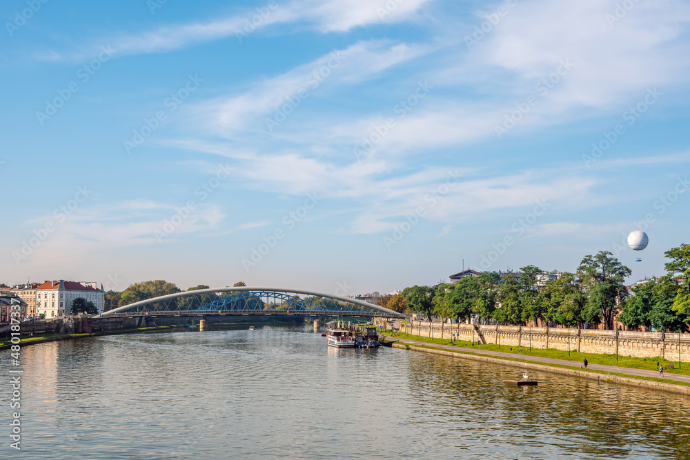 Vistula River in Krakow and Father Bernatek Footbridge, pedestrian promenade on the right bank of the river. View in a sunny October day.