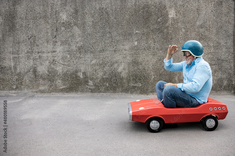 Funny businessman driving retro pedal car outdoor Funny businessman driving retro pedal car outdoor