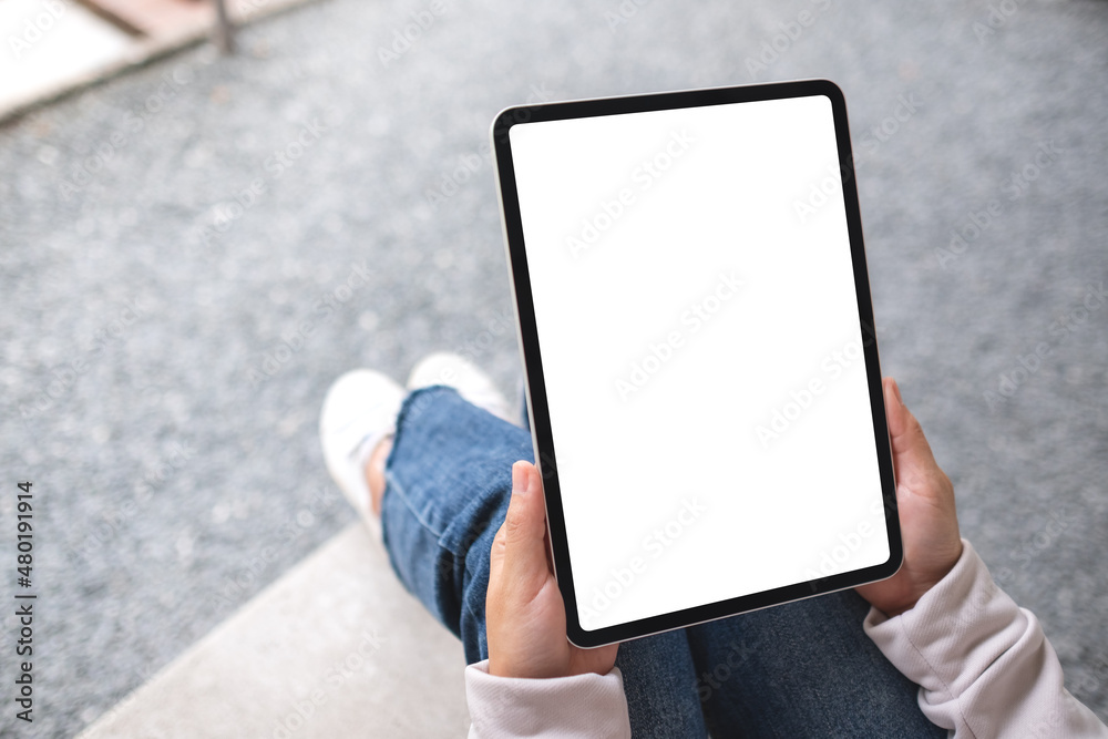 Mockup image of a woman holding digital tablet with blank white desktop screen in the outdoors