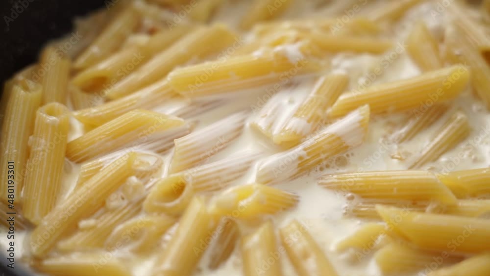 Cook adding cream to boiling pasta Cook adding cream to boiling pasta