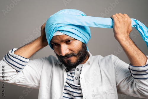 indian sikh man wearing treditional turban at grey background - concept of religion custume and identity.