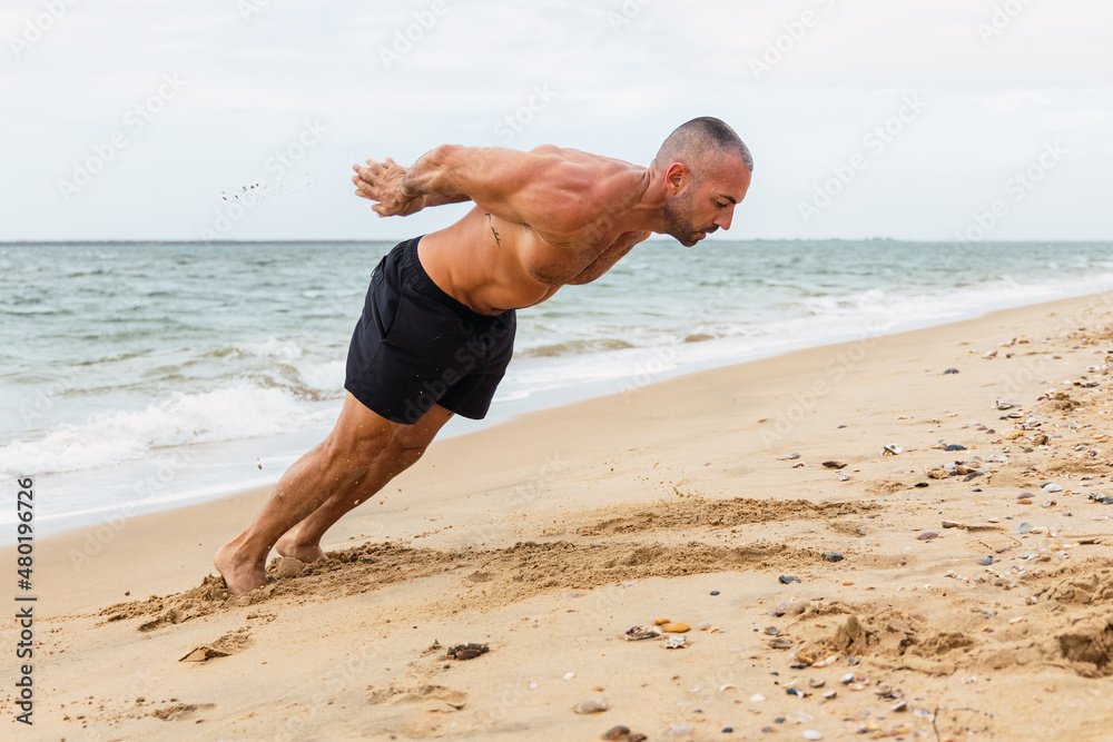 Shirtless sportsman doing clapping push ups on shore Shirtless sportsman doing clapping push ups on shore