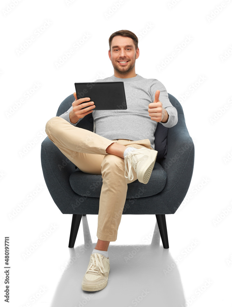 people, technology and furniture concept - happy smiling man with tablet pc computer sitting in chair and showing thumbs up over white background