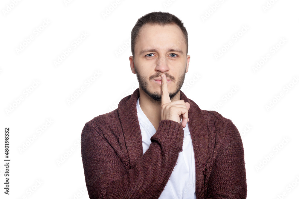 Portrait of young man gesturing silence sign on white background Portrait of young man gesturing silence sign on white background