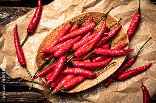 Foto Hot chili peppers on a wooden plate