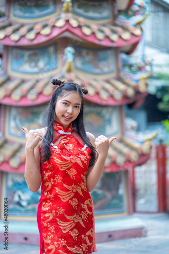 Portrait beautiful Asian girl wearing red traditional Chinese cheongsam decoration at Chinese shrine for Chinese New Year Festival © somchairakin