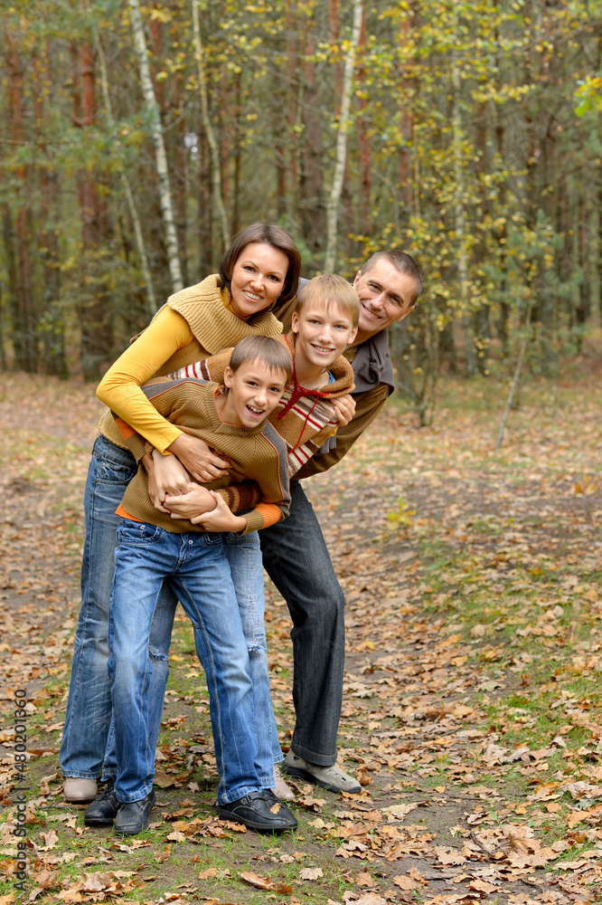 Portrait of family of four posing in autumn forest