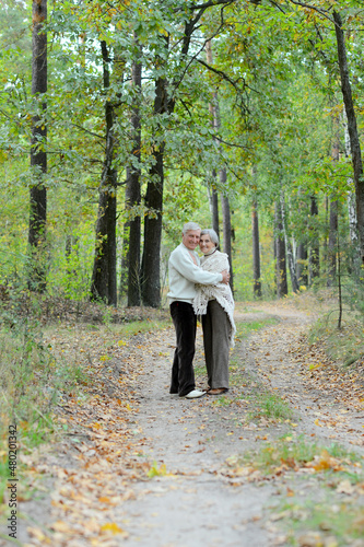 Happy senior couple walking in autumn forest