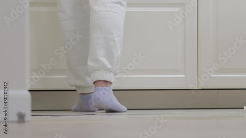 Wallpaper Mural Woman cooking dinner on the kitchen counter at home, female legs in sweatpants near the white kitchen cabinet. High quality 4k footage Torontodigital.ca