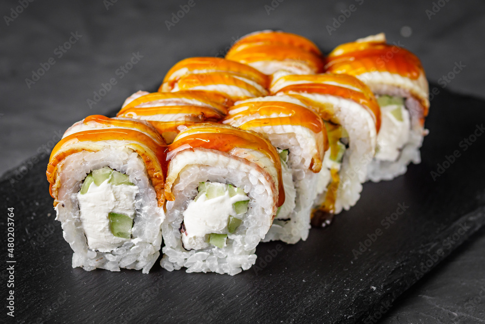 appetizing Philadelphia sushi roll with eel and cucumber on a black stone plate appetizing Philadelphia sushi roll with eel and cucumber on a black stone plate