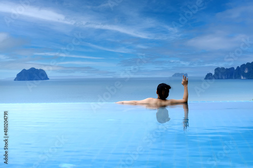 Woman cheerful  swimming in water of pool looking away on background of sea   back view