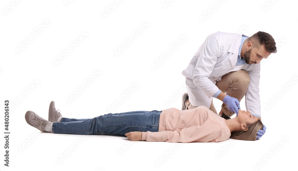 Doctor in uniform performing first aid on unconscious woman against white background Doctor in uniform performing first aid on unconscious woman against white background