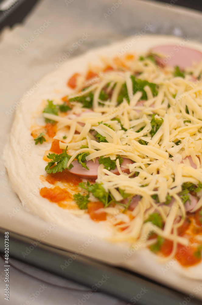 homemade pizza with grated cheese on a baking sheet with blurred edges homemade pizza with grated cheese on a baking sheet with blurred edges
