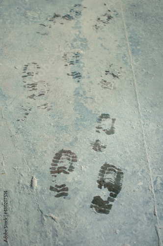 wet bootprints on dirty concrete floor in vertical format photo