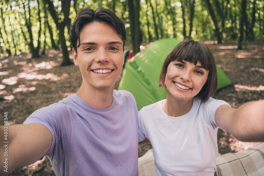Photo portrait young couple taking selfie smiling in green summer forest near tent camping Photo portrait young couple taking selfie smiling in green summer forest near tent camping