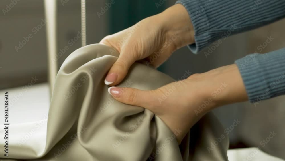 Woman Checking The Quality Of Shiny Smooth Fabric Satin, Tencel, Cotton, Bamboo, Close-up. Female Hand Strokes Silky Luxury Satin Bed Linen, Smooth Shiny Fabric, Silk Material. Woman Checking The Quality Of Shiny Smooth Fabric Satin, Tencel, Cotton, Bamboo, Close-up. Female Hand Strokes Silky Luxury Satin Bed Linen, Smooth Shiny Fabric, Silk Material.