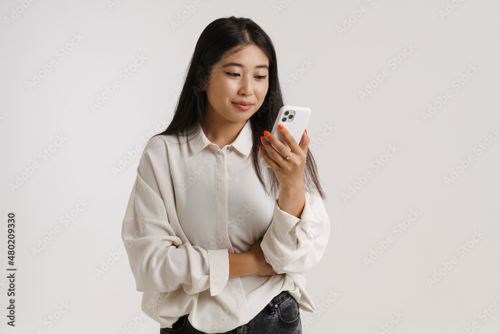 Young asian woman smiling and using mobile phone Young asian woman smiling and using mobile phone