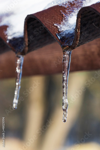 beautiful icicles shine in the sun. spring landscape with icicles hanging from the roof of the house. © mihail39