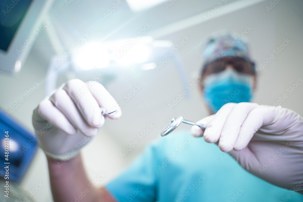 Dentist handling dental tools in patient's view Dentist handling dental tools in patient's view