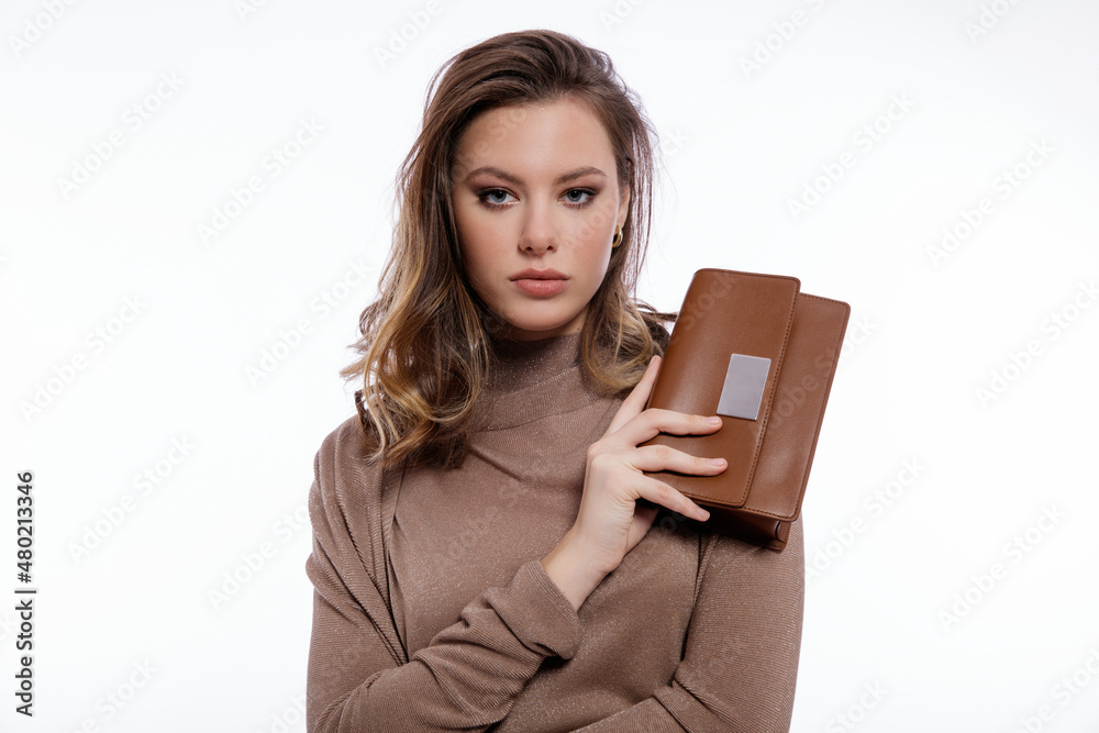 High fashion photo of a beautiful elegant young woman in a pretty long beige brown dress, cardigan, handbag, clutch posing on white background. Studio shot. Slim figure, make up, hair, shiny curls High fashion photo of a beautiful elegant young woman in a pretty long beige brown dress, cardigan, handbag, clutch posing on white background. Studio shot. Slim figure, make up, hair, shiny curls