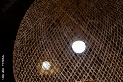 close up creative craft led lamp inside the Thailand local traditional brown bamboo pattern lamp in the dark night.