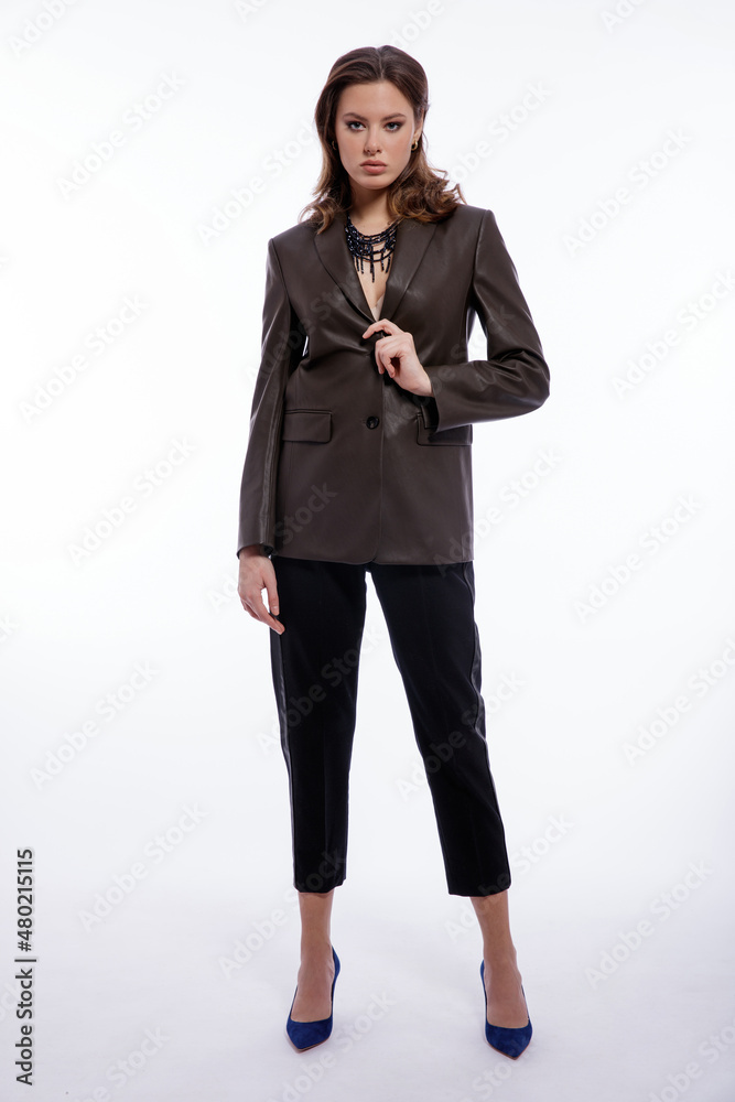 High fashion photo of beautiful elegant young woman in a pretty suit, leather dark olive khaki jacket, trousers, pants posing on white background. Studio shot. Slim figure, luxury hair, shiny curls High fashion photo of beautiful elegant young woman in a pretty suit, leather dark olive khaki jacket, trousers, pants posing on white background. Studio shot. Slim figure, luxury hair, shiny curls