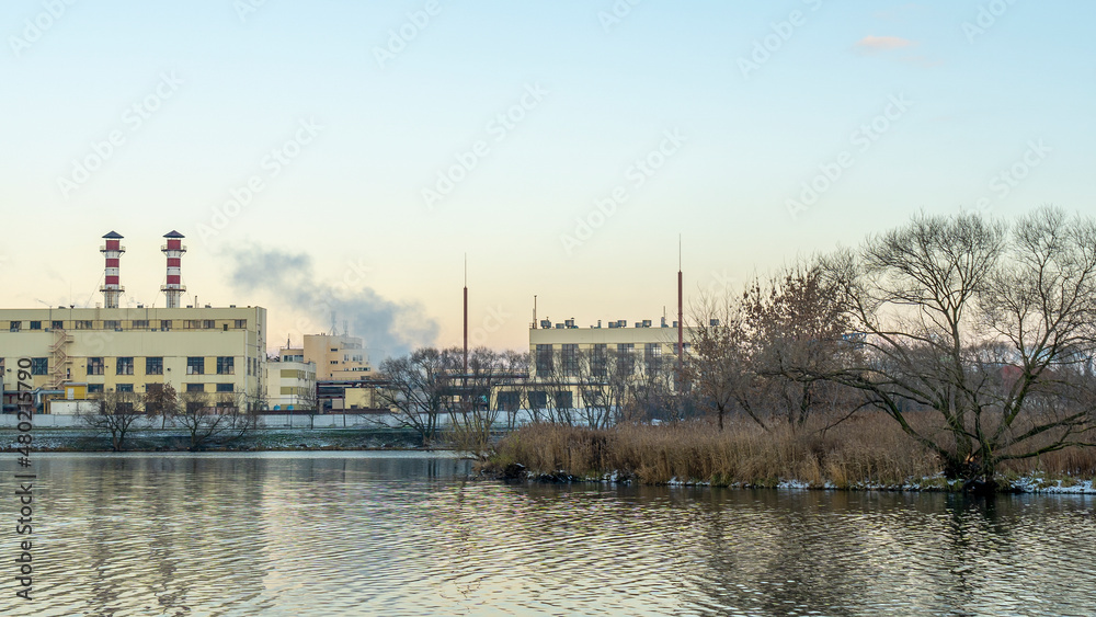 Industrial air pollution. Winter landscape with factory and trees. The concept of environmental pollution.