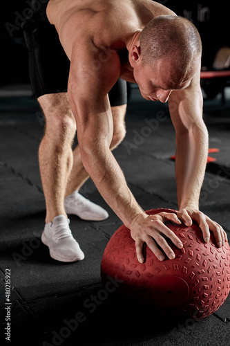 Fitness man working out at indoors modern gym using medicine ball.Shirtless caucasian male with muscular body is stretching with cross fit ball. sport, fitness, weight loss, cross fit concept