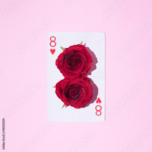 Playing card. Eight of hearts with number eight made from red roses on pink pastel background. Flatlay. Woman's day inspiration. Gambling mood.