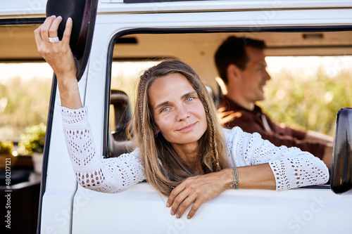 Cute young Caucasian woman, traveler on road trip with husband,get out of camping van window in the morning. Cosy comfortable setup in camper van. Millennial travel trend, adventure on the road.