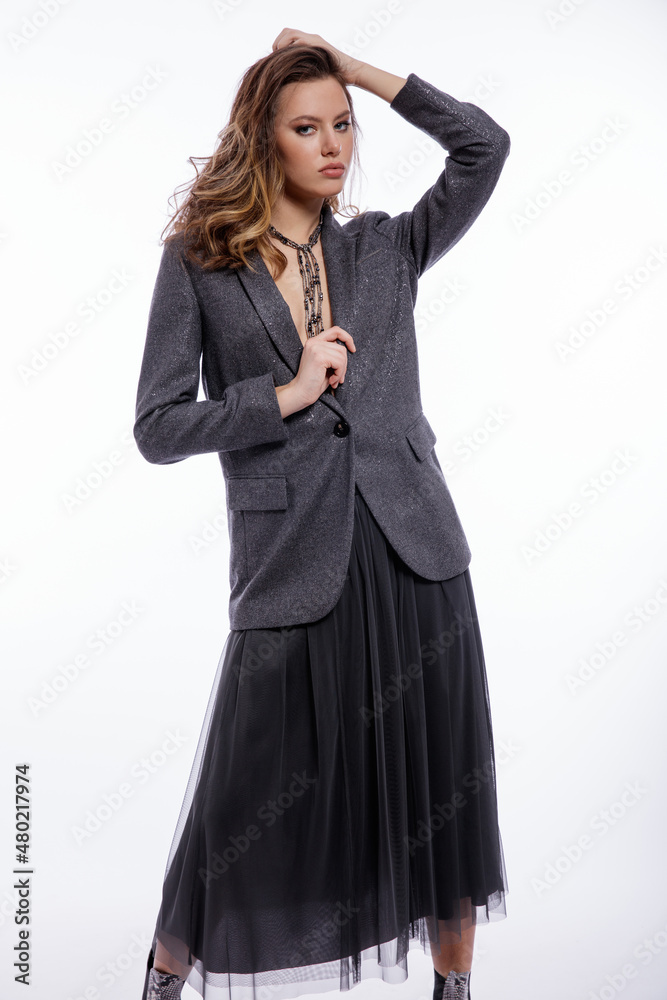 High fashion photo of beautiful elegant young woman in a pretty suit, gray sequined jacket, long skirt, snake skin boots, necklace posing on white background. Studio shot. Luxury hair, shiny curls High fashion photo of beautiful elegant young woman in a pretty suit, gray sequined jacket, long skirt, snake skin boots, necklace posing on white background. Studio shot. Luxury hair, shiny curls