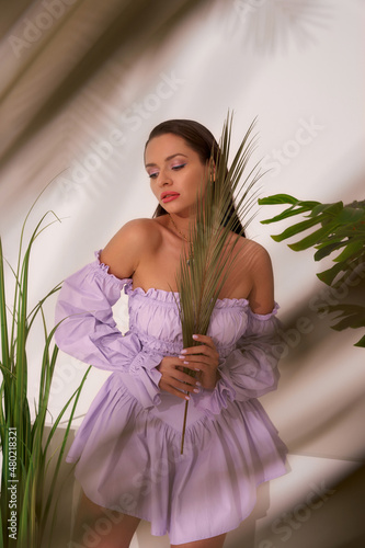 Pretty languid woman model in stylish purple bodice with trumpet sleeves holds p Fototapet
